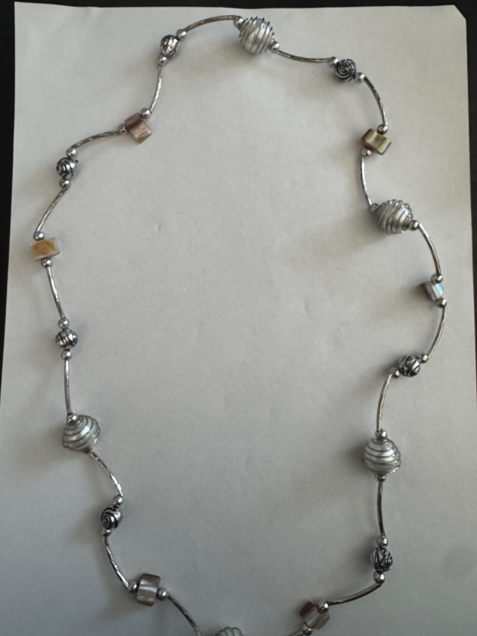Langere ketting met bruine schelpkralen, parels en zilverkleurige buisjes