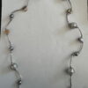 Langere ketting met bruine schelpkralen, parels en zilverkleurige buisjes