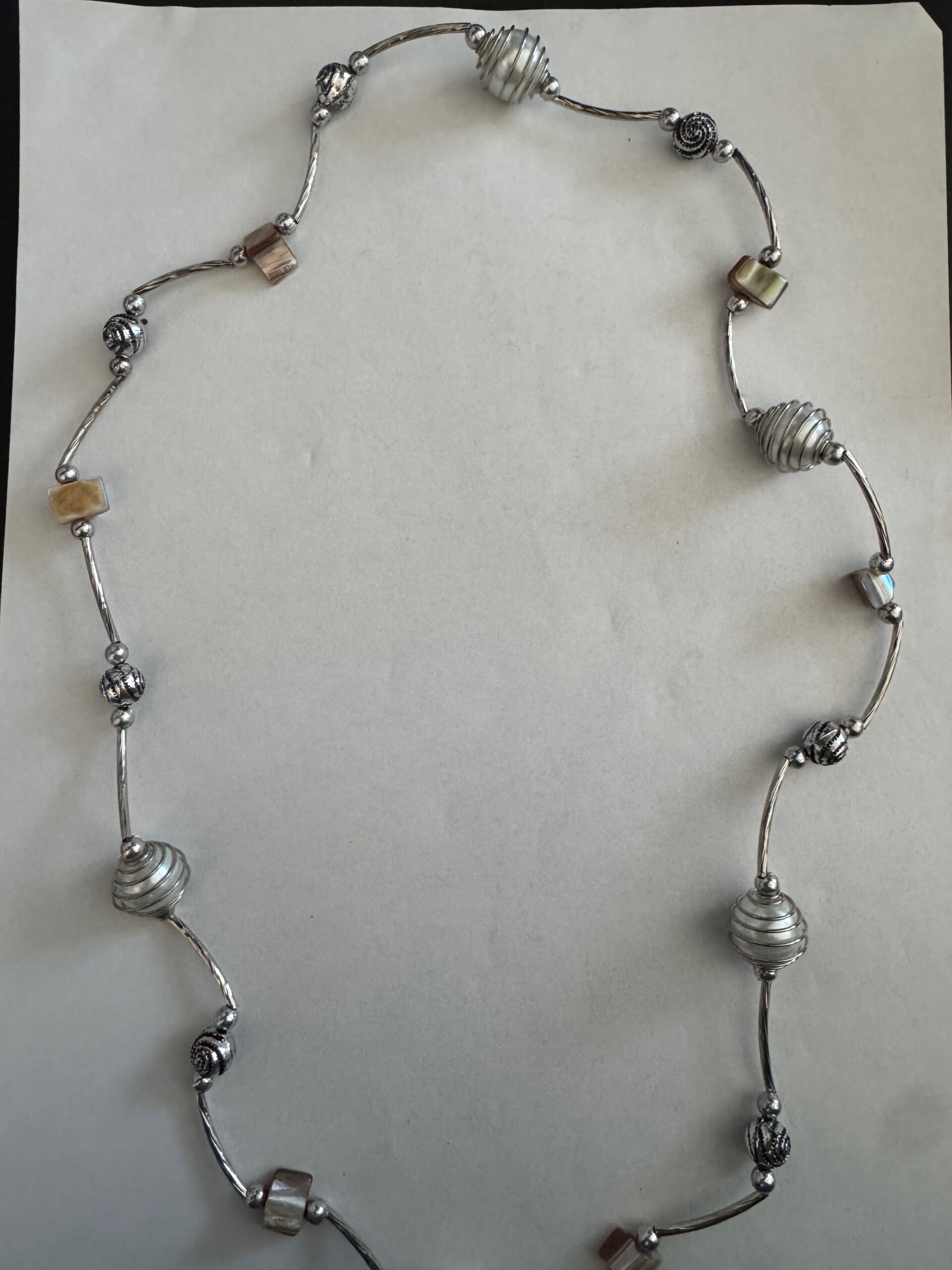 Langere ketting met bruine schelpkralen, parels en zilverkleurige buisjes