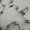 Langere ketting met bruine schelpkralen, parels en zilverkleurige buisjes