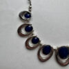 Mooie zilverkleurige ketting met blauwe hangers in verdeler
